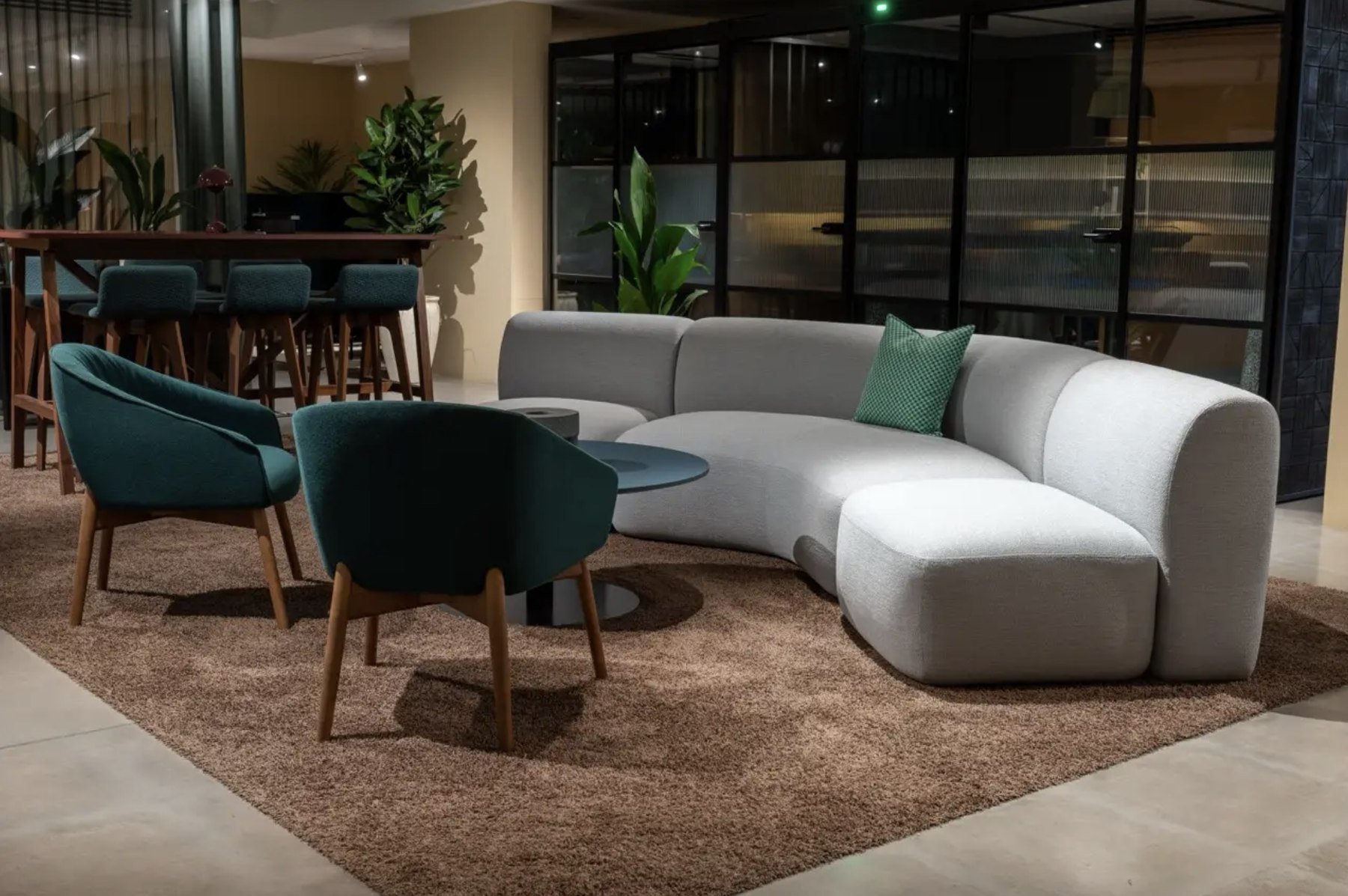 Curved modular sofa and teal lounge chairs in a commercial breakout area